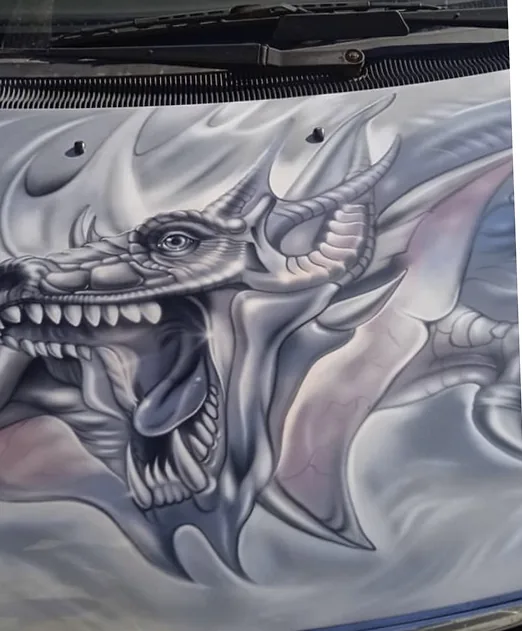 Greyscale dragon airbrushed across a car hood