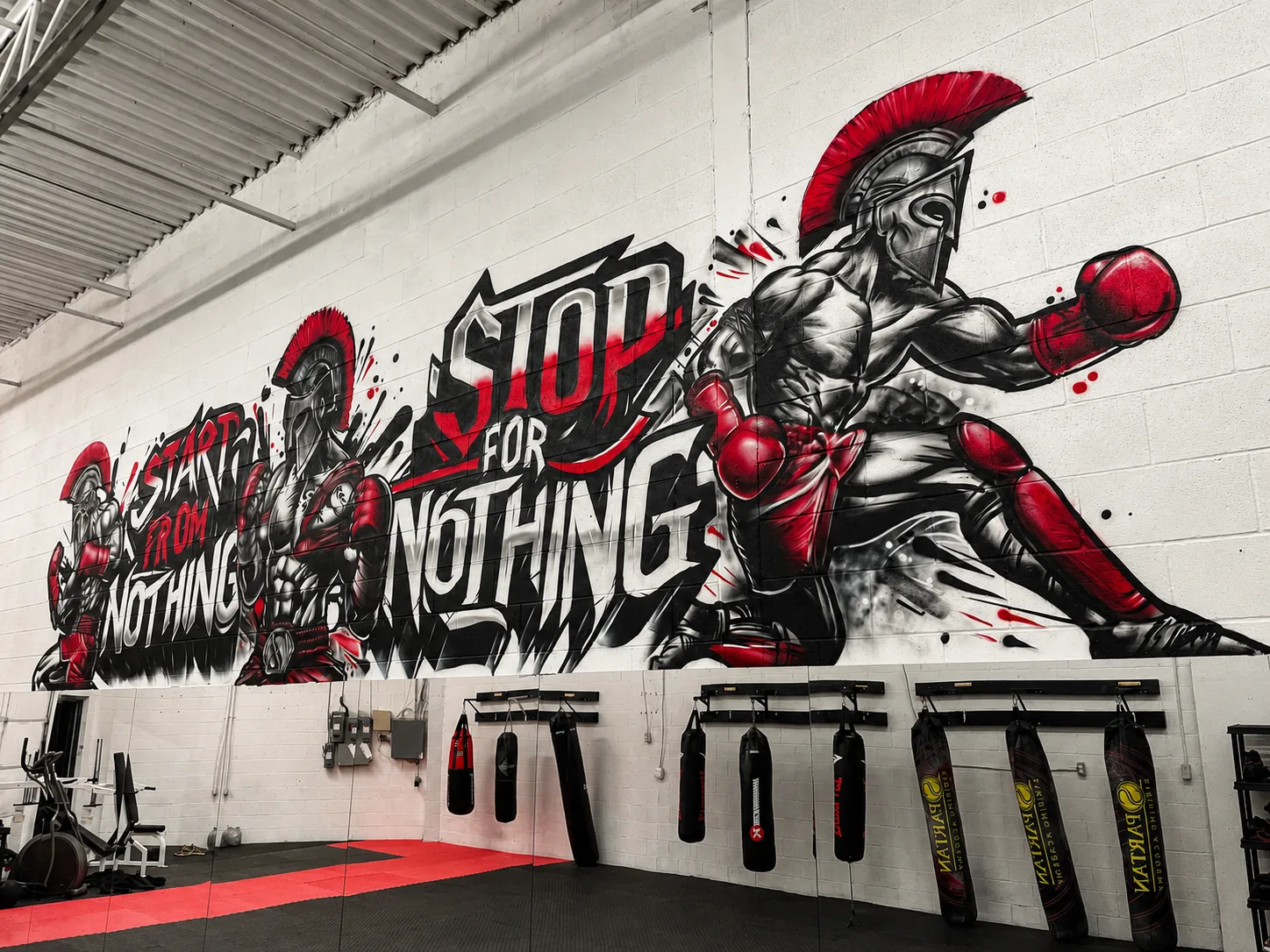 Spartan warrior boxing mural — 'Stop For Nothing' — above the heavy bags