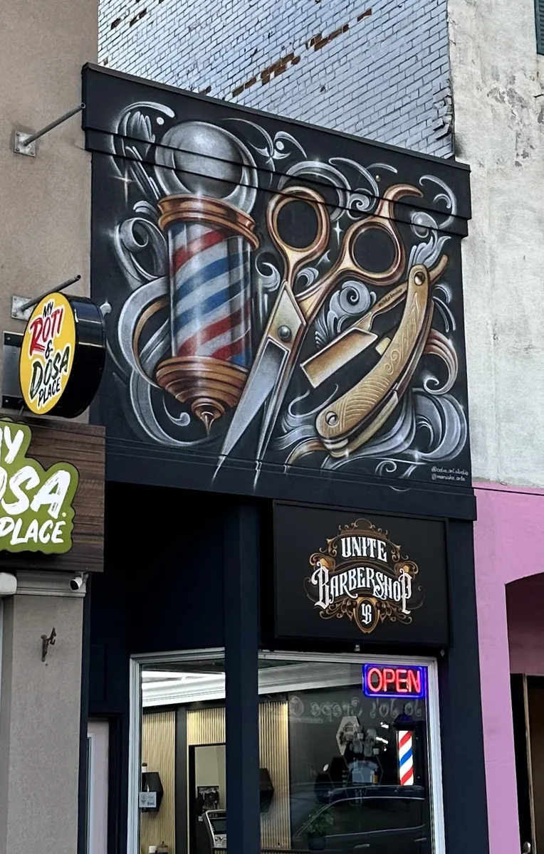 Hand-painted barbershop facade — pole, scissors and razor above the shopfront